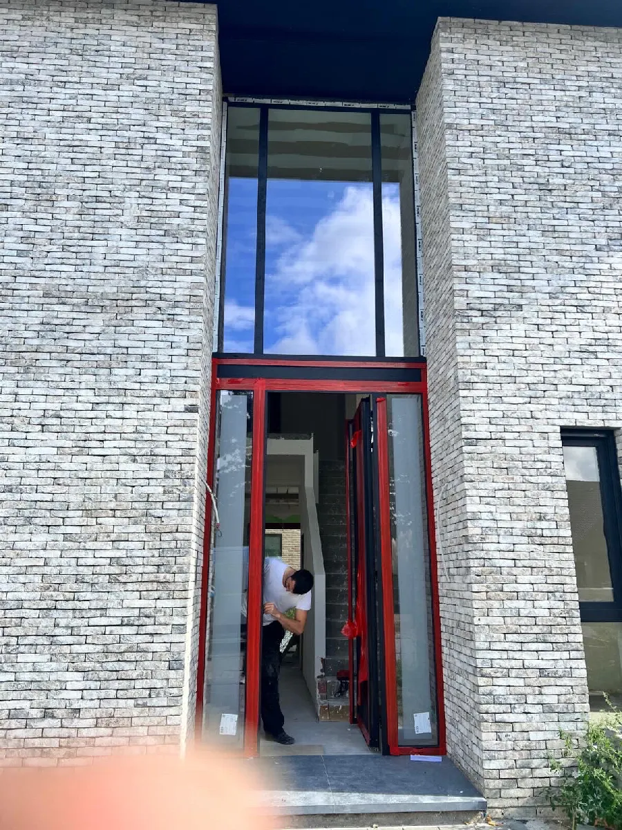 Porte d'entrée et châssis fixe en aluminium posés par Novaris sur une façade en brique